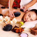 Adult woman having hot stone massage in spa salon